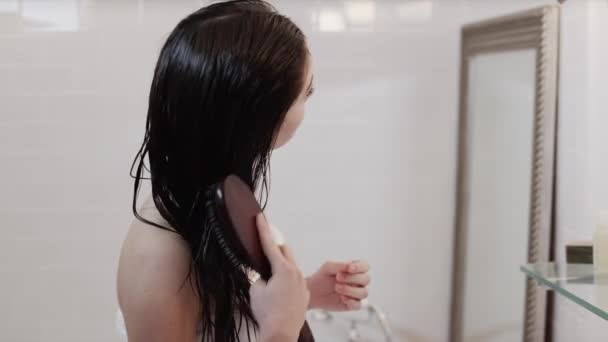 Жінка чистить волосся у ванній — стокове відео