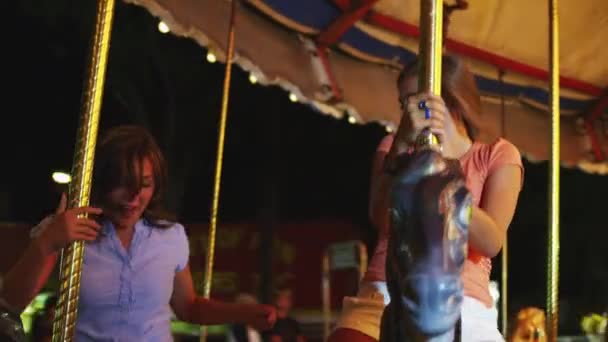 Girls riding carousel in amusement park — Stock Video