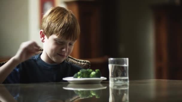 Мальчик смотрит на брокколи на тарелке — стоковое видео