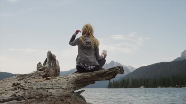 Donna che beve caffè sul tronco al lago — Video Stock