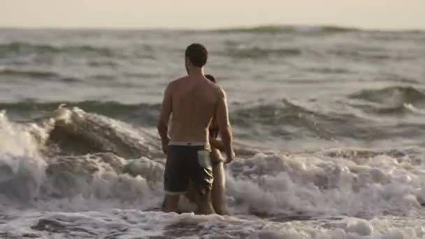 Casal brincando em ondas oceânicas na praia — Vídeo de Stock