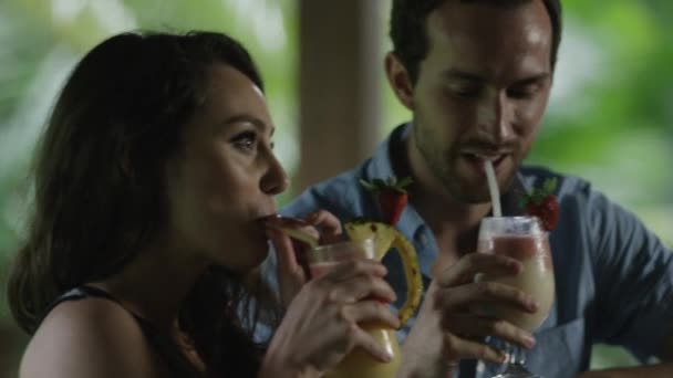 Paar stößt mit tropischen Getränken in Bar an — Stockvideo