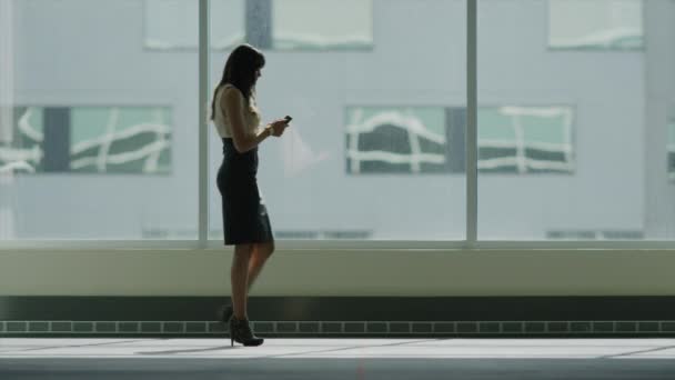 Бізнес-леді, що ходить і використовує мобільний телефон — стокове відео