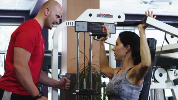 Fysieke trainer helpen vrouw uitoefenen in de sportschool — Stockvideo