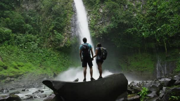 Coppia ammirando cascata nella foresta pluviale — Video Stock