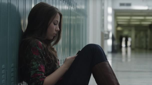 Девушка сидит в школе и с помощью телефона — стоковое видео