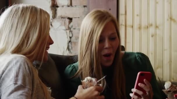 Frauen schauen aufs Telefon und essen Eis — Stockvideo