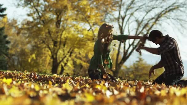 男人和年轻女人把叶子扔在公园 — 图库视频影像