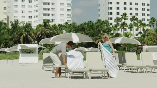 Paar entspannt sich auf Liegestühlen am Strand — Stockvideo