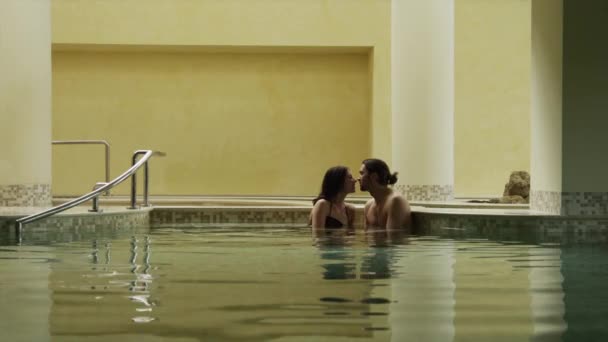 Пара поцелуев в закрытом бассейне — стоковое видео