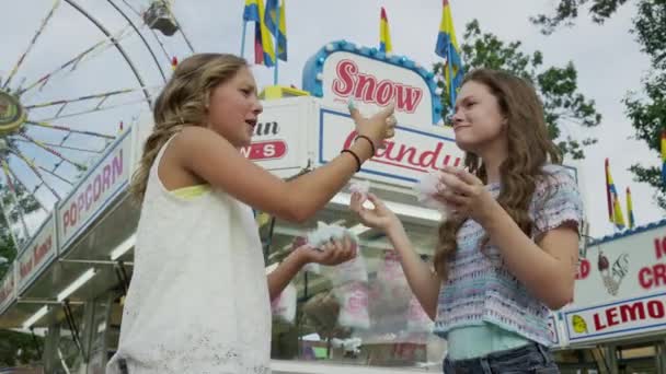 Meisjes katoen snoepjes eten op de kermis — Stockvideo