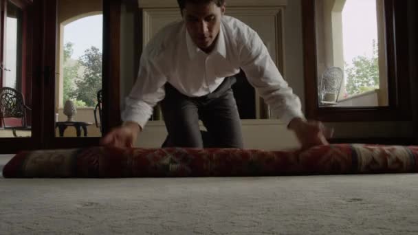 Man unrolling rug in living room — Stock Video