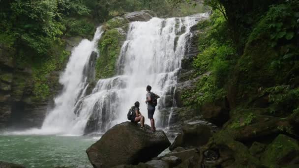 Couple admiring waterfall in rain forest — Stock Video