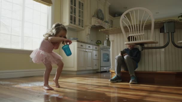 Девочка роняет чашку на пол кухни — стоковое видео
