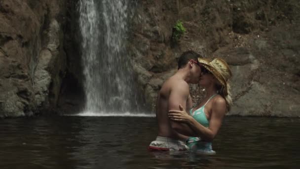 Paar küsst sich mit Wasserfall im Hintergrund — Stockvideo