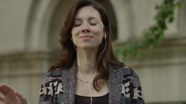 Женщина слушает музыку на улице в наушниках — стоковое видео