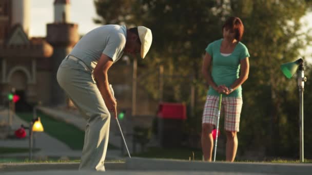 Homem batendo bola de golfe em buraco — Vídeo de Stock