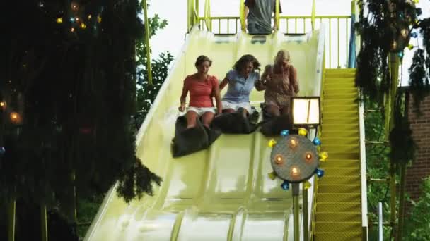 Chicas bajando deslizarse en el parque de atracciones — Vídeo de stock