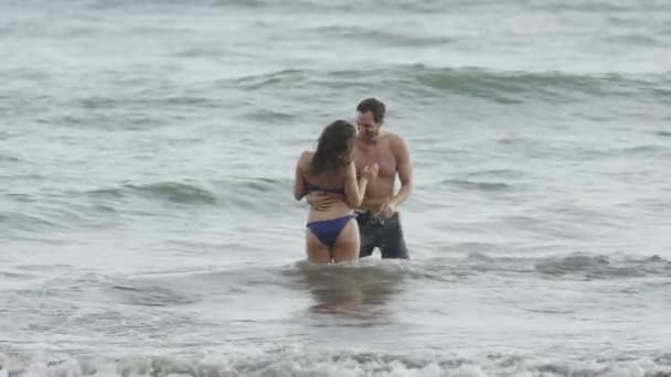 Pareja besándose en ocean waves — Vídeo de stock