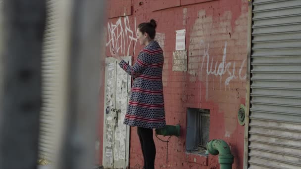 Vrouw met behulp van telefoon vóór graffiti — Stockvideo