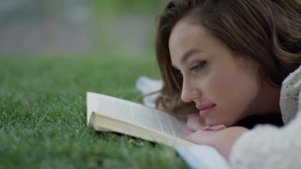 Frau liest Buch im Gras — Stockvideo