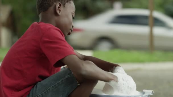 Мальчик сжимает губку над ведром — стоковое видео