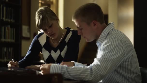 Twee studenten huiswerk in bibliotheek — Stockvideo