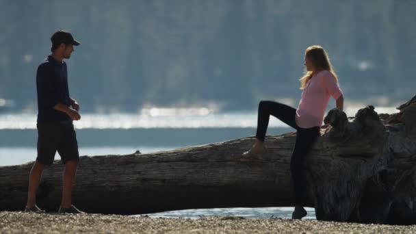Mann fotografiert Freundin auf Baumstamm am See — Stockvideo
