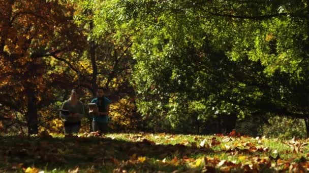 Two women carrying books in park — Stock Video