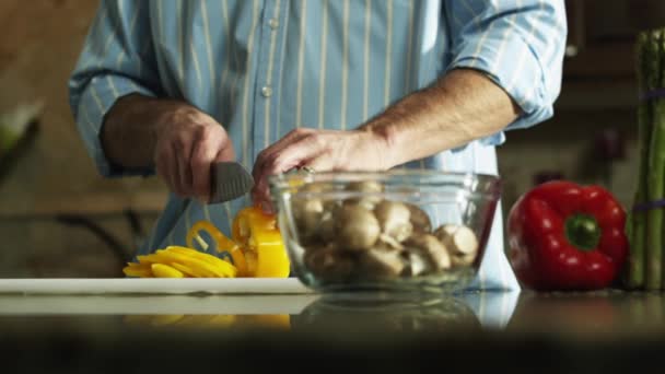 Hombre corte pimiento amarillo en la cocina — Vídeos de Stock