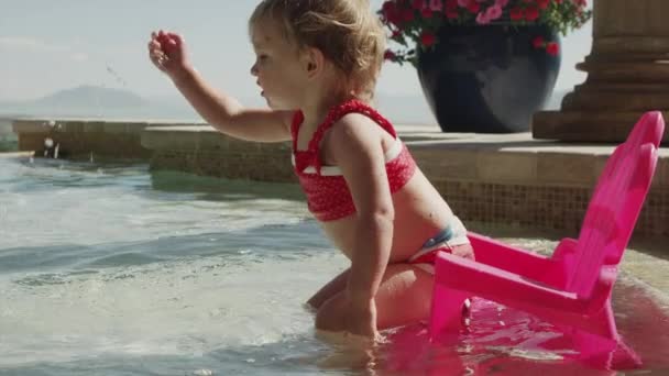 Meisje van de baby spetteren in zwembad — Stockvideo