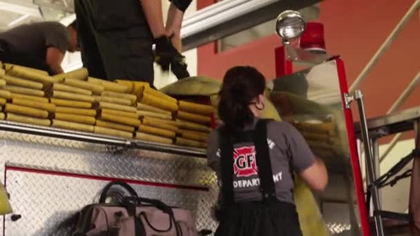 Bomberos rodando en manguera en la parte superior del camión de bomberos — Vídeos de Stock