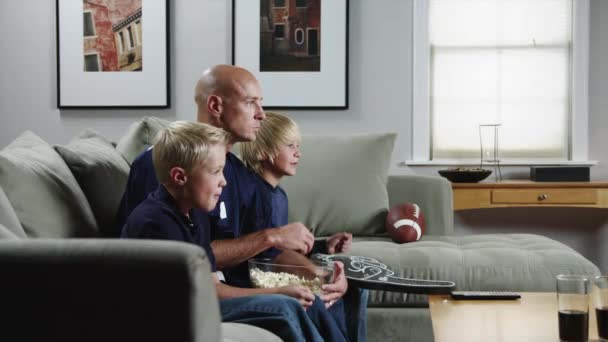 Отец с сыновьями смотрит матч по телевизору — стоковое видео