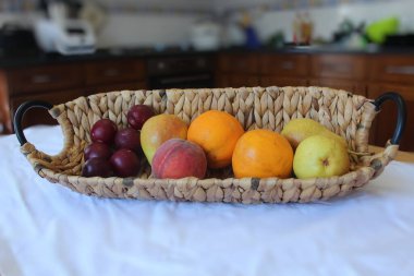 İçinde meyve portakalları olan bir sepet şeftali, şeftali, meyve portakallı bir sepet şeftali, armut ve mutfak arka planda.