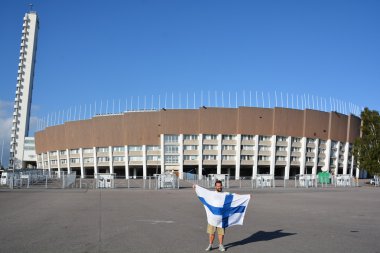Helsinki Finlandiya 09: 25 2015: Olimpiyat stadyumunun önünde Fin bayrağı sallayan ve 1952 Yaz Olimpiyatları 'nda ülkenin en büyük stadyumu olan kule