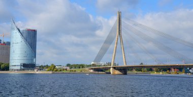 RIGA LATVIA SEPTEMBER 18 2015: The Vansu Bridge in Riga is a cable-stayed bridge that crosses the Daugava river in Riga and Swedbank office building sheer height and sleek silhouette. 