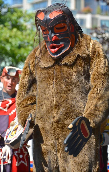 VICTORIA BC CANADA JUNE 24 2015: Native Indian man in traditional costume and wooden mask. First Nations in BC constitute a large number of First Nations governments and peoples in the province of BC