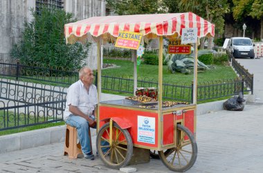 ISTANBUL TURKEY SEPT 28: Man sells roasted maroons for to live in down town Istanbul Turkey on september 28 2013. Street vendors are omnipresent on Istanbul street.