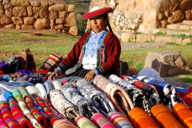 NEAR CUSCO PERU-NOVEMBER 15:Quechua woman dressed in traditional clothing sale colorful tablecloths and fabric on November 15, 2010 in Cusco Peru. The national rural poverty rate is over 50 per cent.