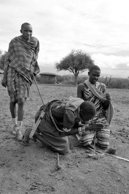 Amboseli, Kenya-Ekim 13: Genç Masai savaşçılarının portresi, Kenya 'nın Masai Mara kentinde 13 Ekim 2011' de köylerini ziyaret eden misafirlere geleneksel bir şekilde nasıl ateş yaktıklarını gösteriyor..