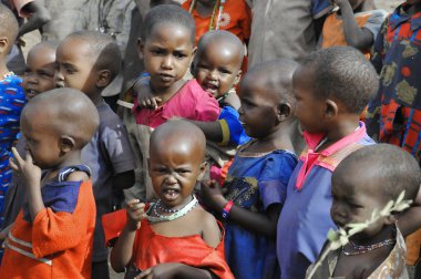 AMBOSELI, KENYA - 13 Ekim 2011 Masai Mara, Kenya 'da inek gübresiyle yapılan evde yaşayan kimliği belirsiz Afrikalı çocuklar. Kenya 'nın% 58' i günde 2 dolardan az parayla yaşıyor.