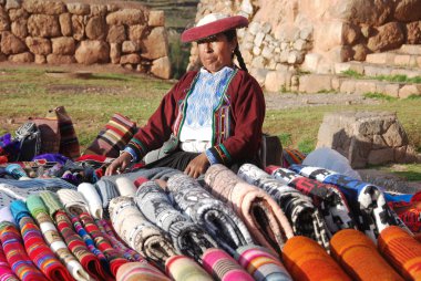 NEAR CUSCO PERU-NOVEMBER 15:Quechua woman dressed in traditional clothing sale colorful tablecloths and fabric on November 15, 2010 in Cusco Peru. The national rural poverty rate is over 50 per cent.