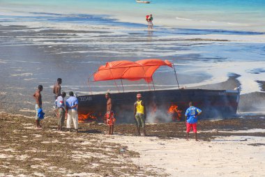 NUNGWI, ZANZIBAR - 23 Ekim: Yerel balıkçı deniz yosunlarından kurtulmak için tekneyi yakıyor, 23 Ekim 2011, Nungwi, Zanzibar, Tanzanya.