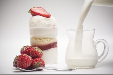 Fresh strawberry and dessert. Pour milk inside the glass clipart