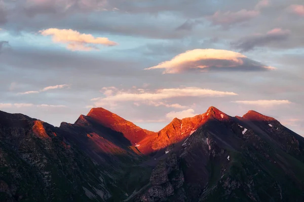 Lenticulaire wolk boven een bergtop in de ondergaande zon — Stockfoto