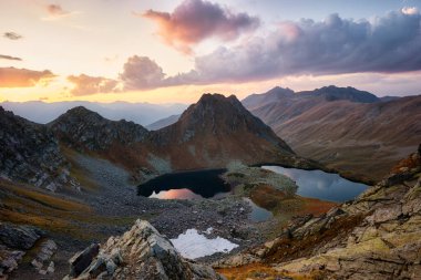 Bulutlarda gün batımında güzel dağlar, altın alp tarlaları, göller ve sıradağlar, seyahat ve dağ hayatı. Göl kenarındaki kamp alanında. Yüksek kalite fotoğraf