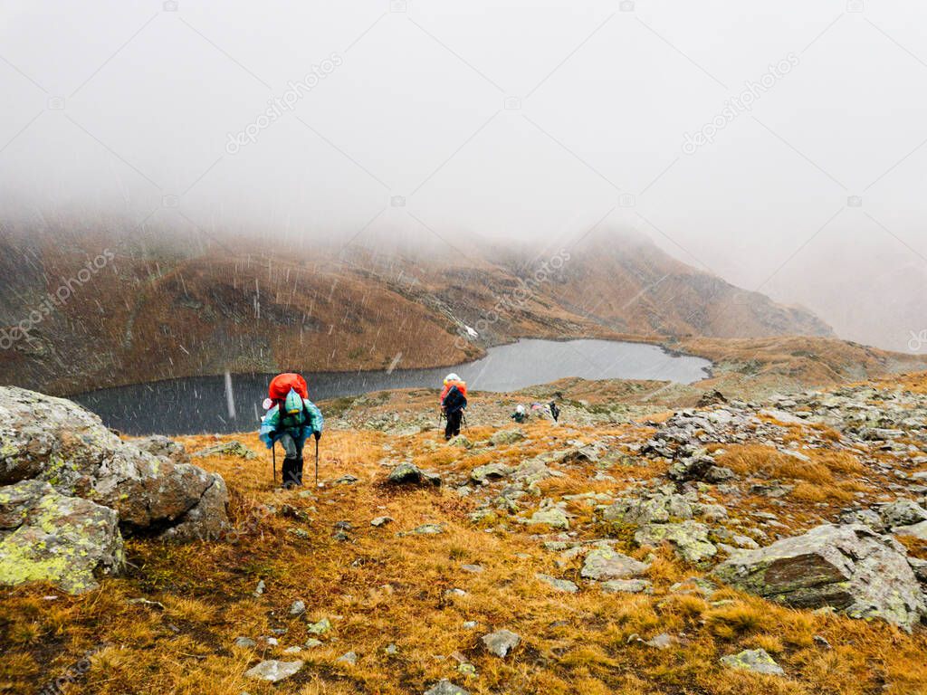 Tourists travelers with backpacks climb the rocks in dense fog. Poor visibility and easy to get lost. Caucasus Mountains, Arkhyz