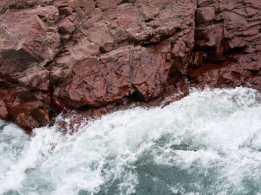 Dağ nehri hızlı bir akarsu ile granit kıyıya vurur. Yüksek kalite fotoğraf