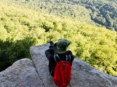 Adam uçurumun kenarındaki bir kayanın üzerinde oturuyor. Yüksek kalite fotoğraf