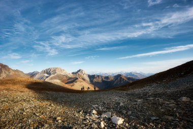 Güneşli sonbaharda Kafkas dağlarının parlak manzarası, bir grup turist yokuş yukarı yükseliyor. Arkhyz, Rusya. Yüksek kalite fotoğraf